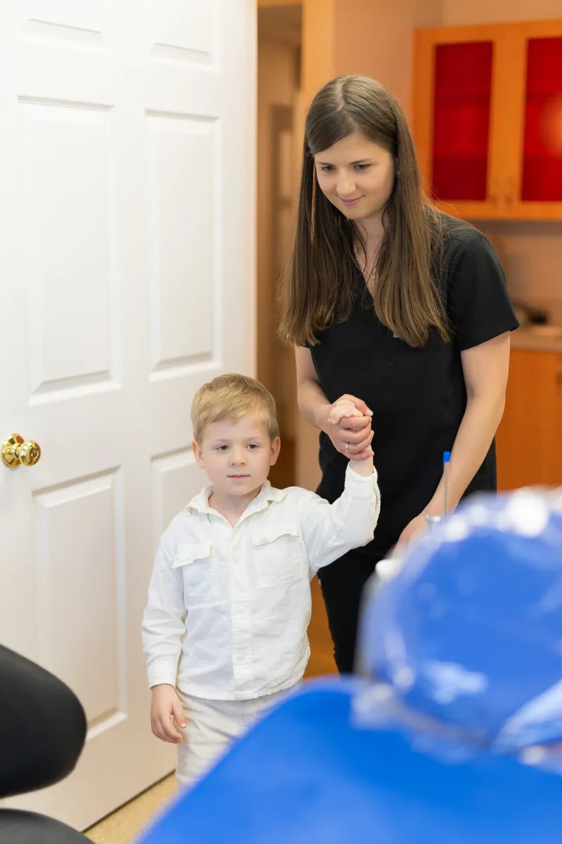 A team member guiding a young patient to a treatment room